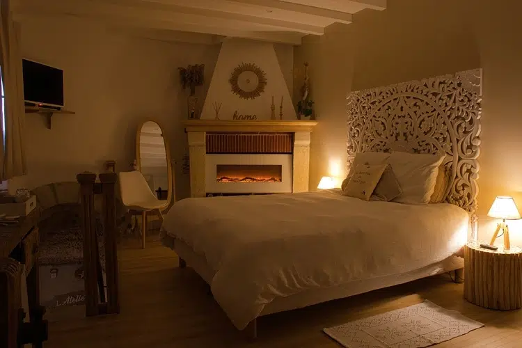 Suite romantique avec lit double et cheminée décorative, ambiance chaleureuse pour un week-end en amoureux